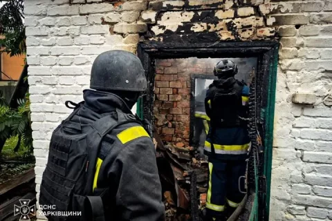 Рятувальники ДСНС біля обгорілого дверного прорізу цегляної будівлі