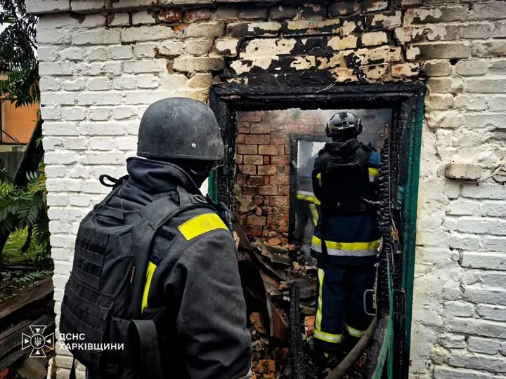 Рятувальники ДСНС біля обгорілого дверного прорізу цегляної будівлі